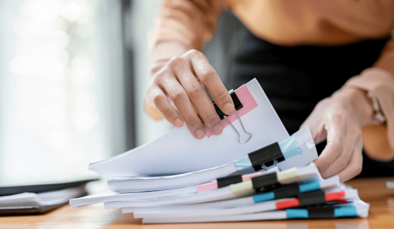 woman sorting through stacks of papers at desk